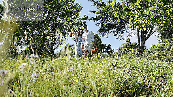 Frau zeigt auf Mann  der auf Gras im Park steht