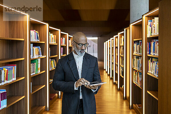 Reifer Geschäftsmann nutzt digitales Tablet in der Bibliothek