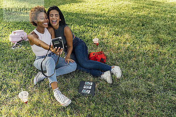 Zwei glückliche Freundinnen machen ein Sofortfoto in einem Park