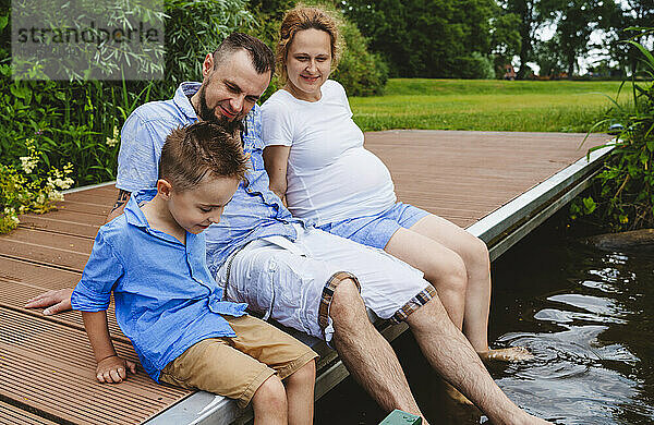 Familie verbringt ihre Freizeit mit der Familie  die auf der Fußgängerbrücke über dem See sitzt