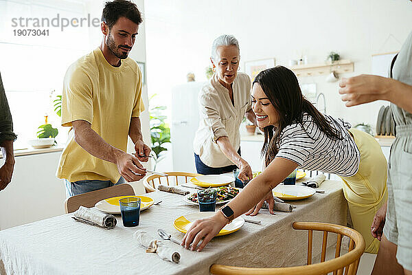 Glückliche Familie deckt Tisch in der Küche