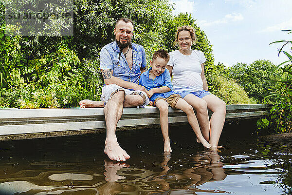 Glückliche Familie verbringt ihre Freizeit auf der Fußgängerbrücke über dem See