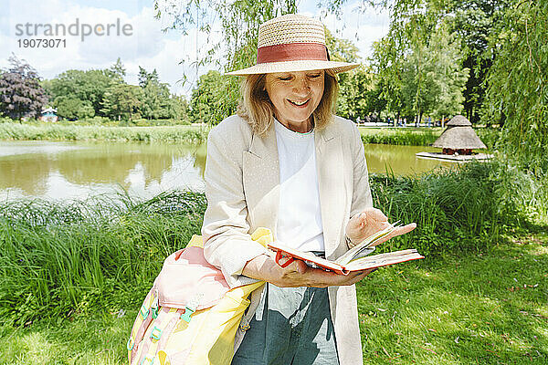 Glückliche Frau mit Hut  die Skizzen im Buch betrachtet