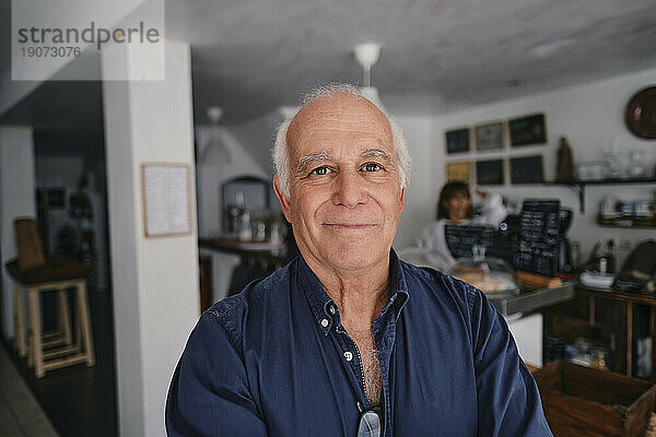 Smiling senior cafe owner in coffee shop