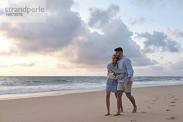 Mann und Frau verbringen ihre Freizeit beim Spaziergang im Sand am Strand
