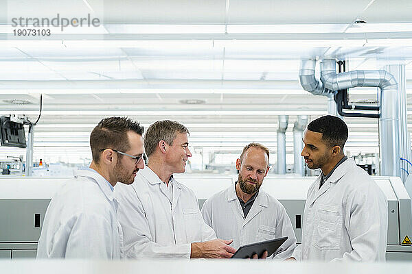 Team kompetenter Elektrotechniker in Laborkitteln trifft sich in der Elektronikfabrik