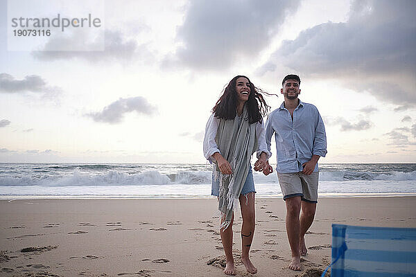 Happy young couple standing on sand at beach