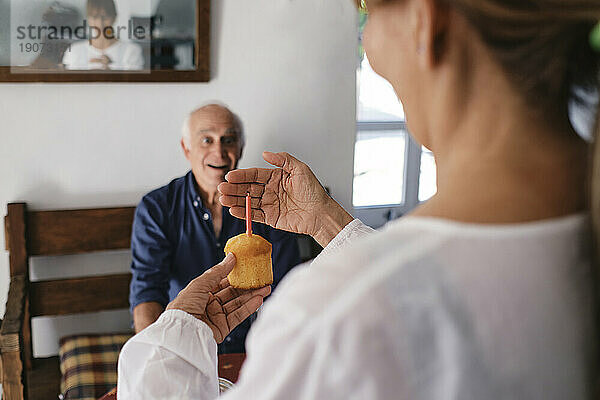 Glückliche Seniorin überrascht Mann mit Cupcake im Café