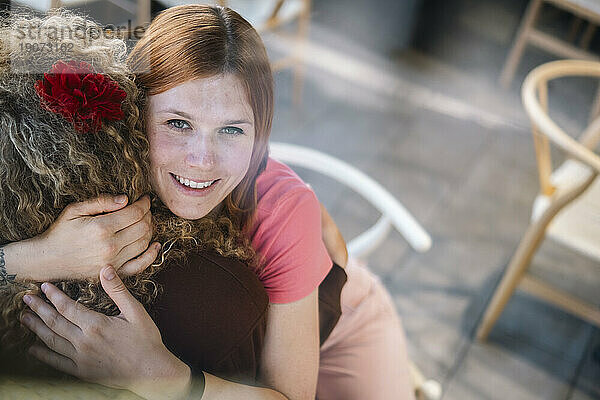 Lächelnde Frau umarmt Freund im Café