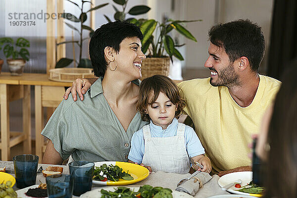Smiling parents with son having lunch on dining table at home
