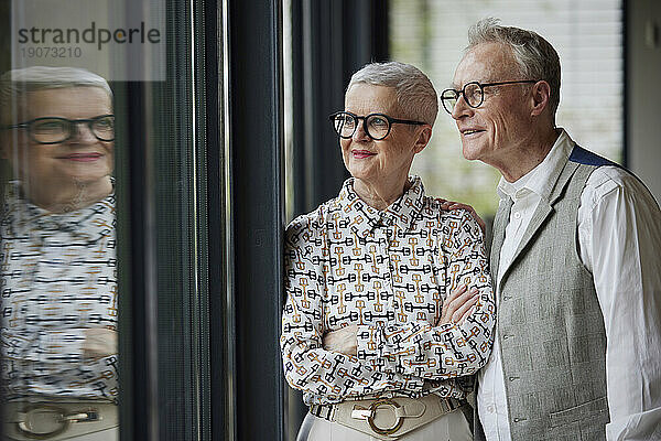 Älteres Paar schaut zu Hause aus dem Fenster
