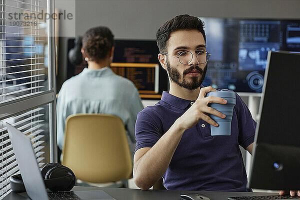 IT-Experte mit Kaffeetasse  der im Büro am Computer arbeitet