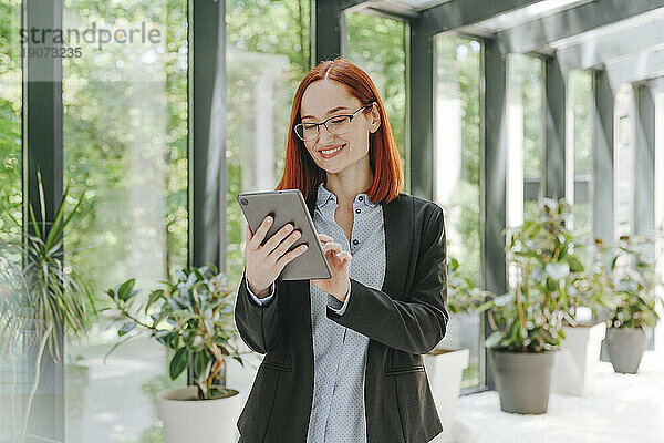 Glückliche Geschäftsfrau nutzt Tablet-PC im Büro