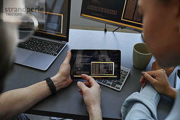 Computerprogrammierer diskutieren gemeinsam über einen Tablet-PC am Schreibtisch