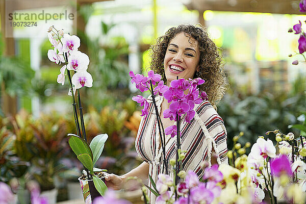Glückliche Frau lacht inmitten von Blumen im Kinderzimmer