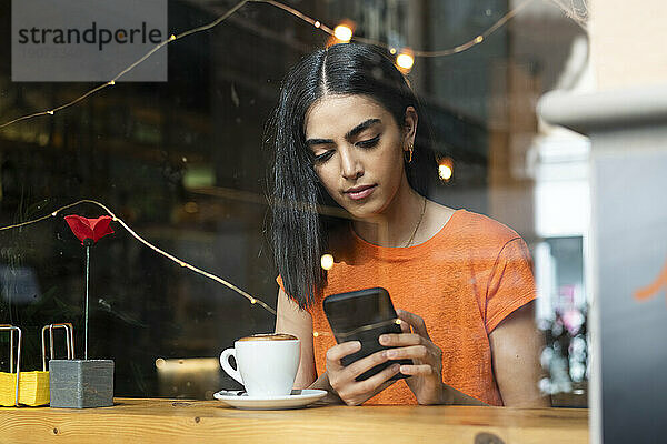 Junge Frau benutzt Smartphone im Café