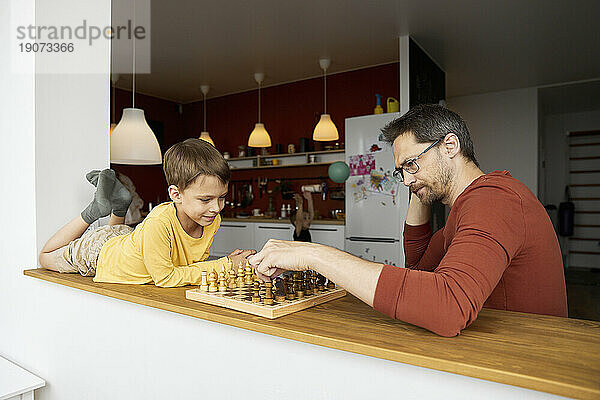 Thoughtful father playing chess with son at home