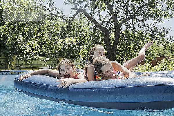 Freunde haben Spaß beim Liegen auf dem Poolfloß im Schwimmbad