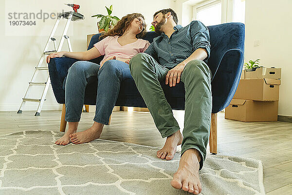 Junges Paar sitzt auf dem Sofa im neuen Zuhause