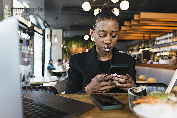 Geschäftsfrau benutzt Smartphone am Tisch im Café