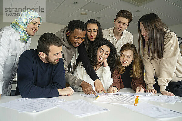 Multiethnische Schüler diskutieren über Notizen auf dem Tisch im Klassenzimmer