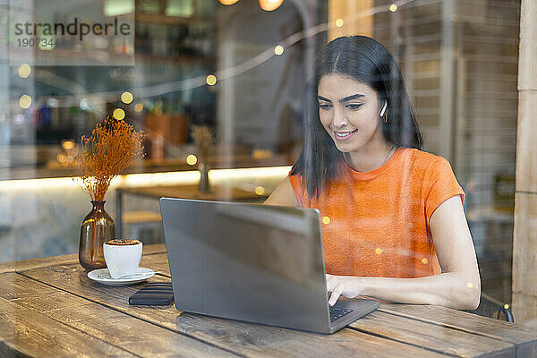 Lächelnder junger Freiberufler  der im Café am Laptop arbeitet