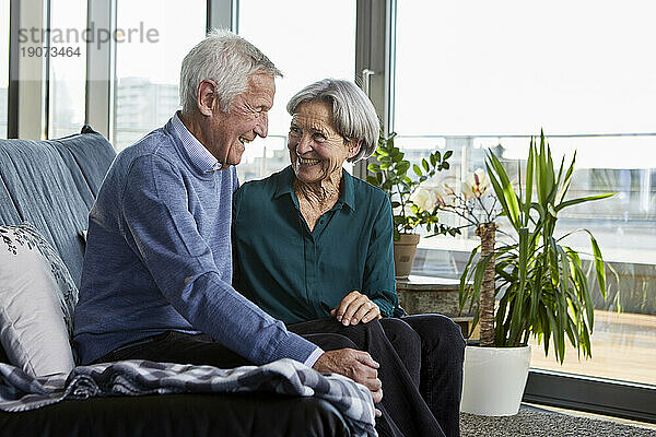 Lachendes älteres Paar sitzt zusammen auf der Couch