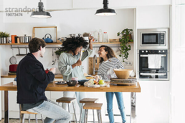 Glückliche Familie bereitet gemeinsam Essen zu  singt und tanzt in der Küche