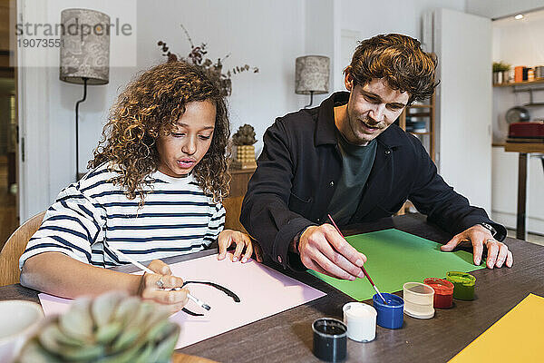 Vater und Tochter sitzen am Tisch und zeichnen und malen gemeinsam