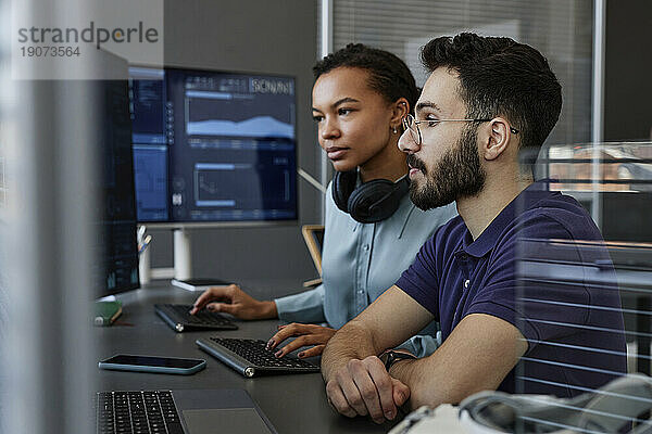 IT-Experten arbeiten gemeinsam am Computer am Schreibtisch