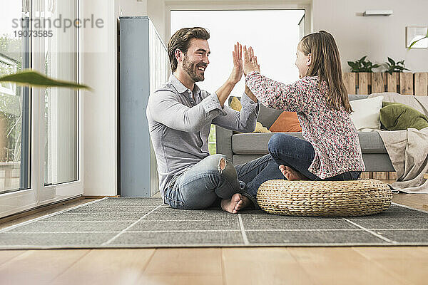 Young man and little girl sitting at home  giving high five