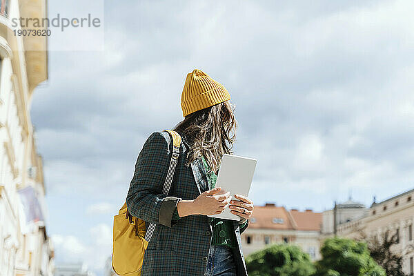 Frau hält Tablet-PC an einem sonnigen Tag unter dem Himmel