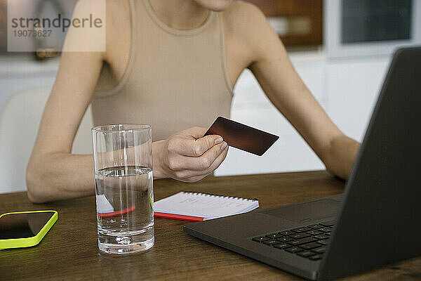 Freiberufler nutzt Kreditkarte für Online-Zahlung auf dem Laptop zu Hause