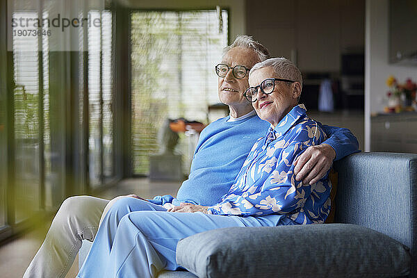 Älterer Mann umarmt Frau auf der Couch zu Hause