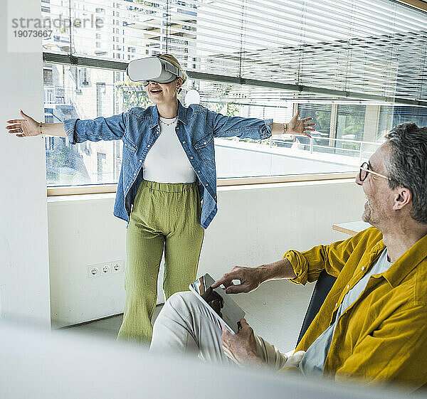 Glücklicher reifer Geschäftsmann mit Kollegen  der Virtual-Reality-Simulatoren im Büro trägt