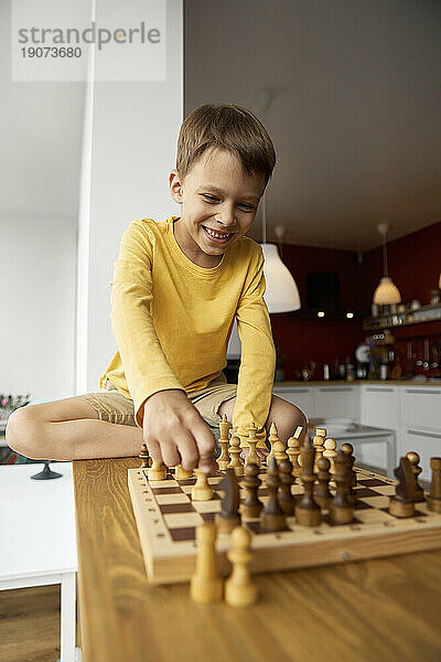 Glücklicher Junge  der zu Hause Schach spielt