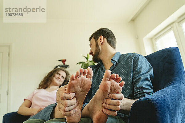 Man massaging feet of girlfriend after moving into new house