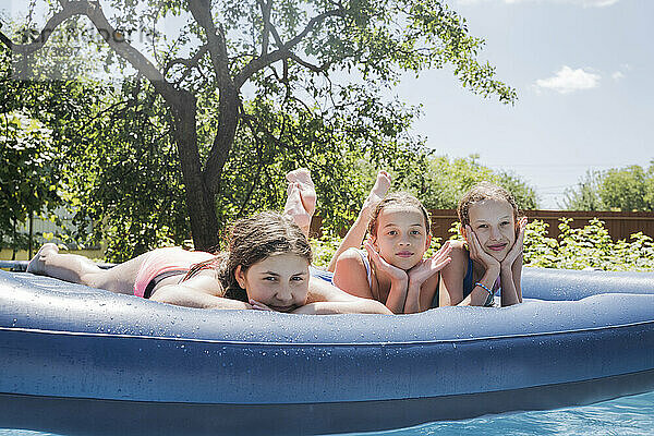 Freunde liegen auf Poolfloß im Schwimmbad
