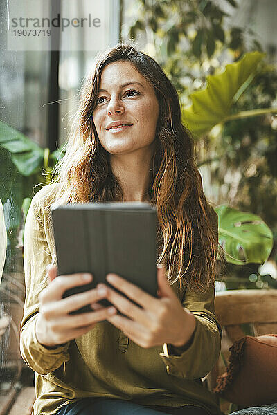 Nachdenkliche Frau hält Tablet-PC im Café