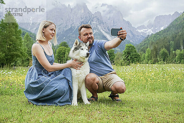 Mann und Frau machen Selfie mit Hund per Smartphone