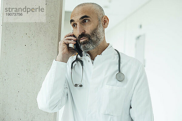 Reifer Arzt  der im Krankenhaus auf dem Smartphone spricht