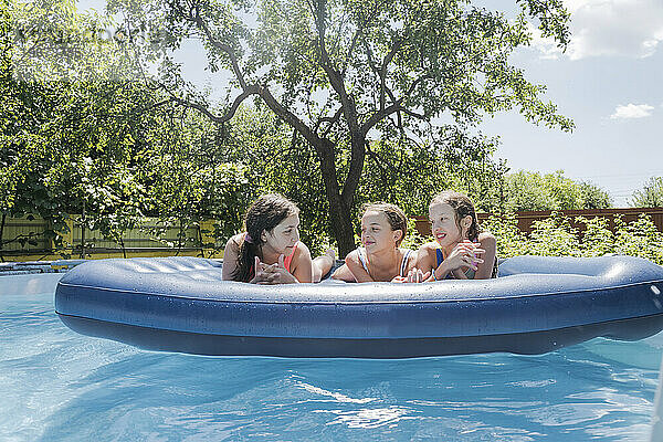 Freunde diskutieren auf Poolfloß im Schwimmbad