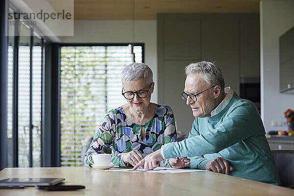 Älteres Paar sitzt zu Hause am Tisch und prüft Dokument