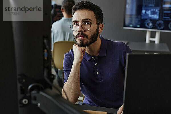 IT-Experte mit der Hand am Kinn  der den Computer im Büro benutzt