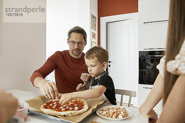 Father and son preparing pizza at home
