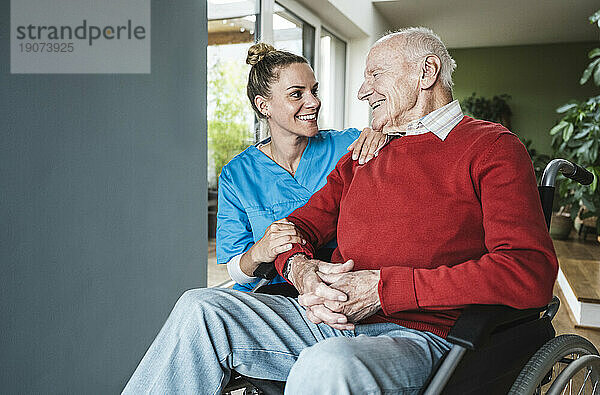 Glückliche Krankenschwester  die sich zu Hause um den älteren Mann kümmert
