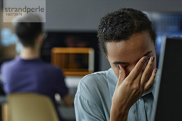 Müder IT-Experte reibt sich im Büro die Augen