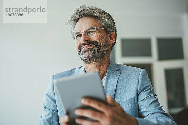Lächelnder Geschäftsmann hält Tablet-PC im Büro