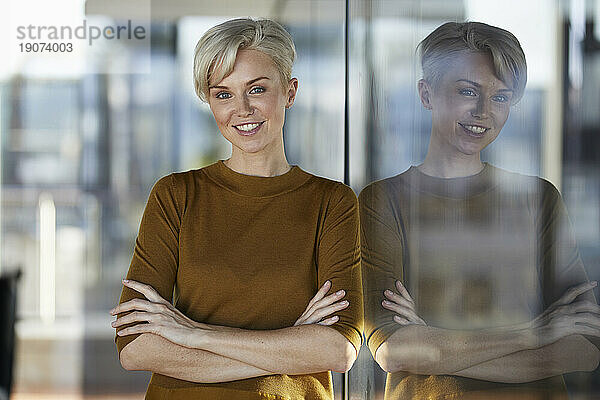 Portrait of smiling woman leaning against window