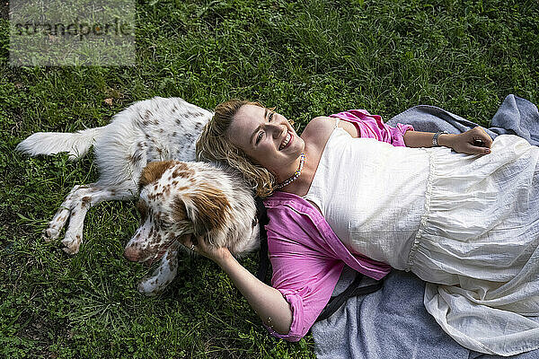 Lächelnde Frau liegt mit Hund im Park